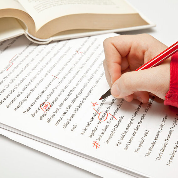 A person is editing a paper with a red pen.